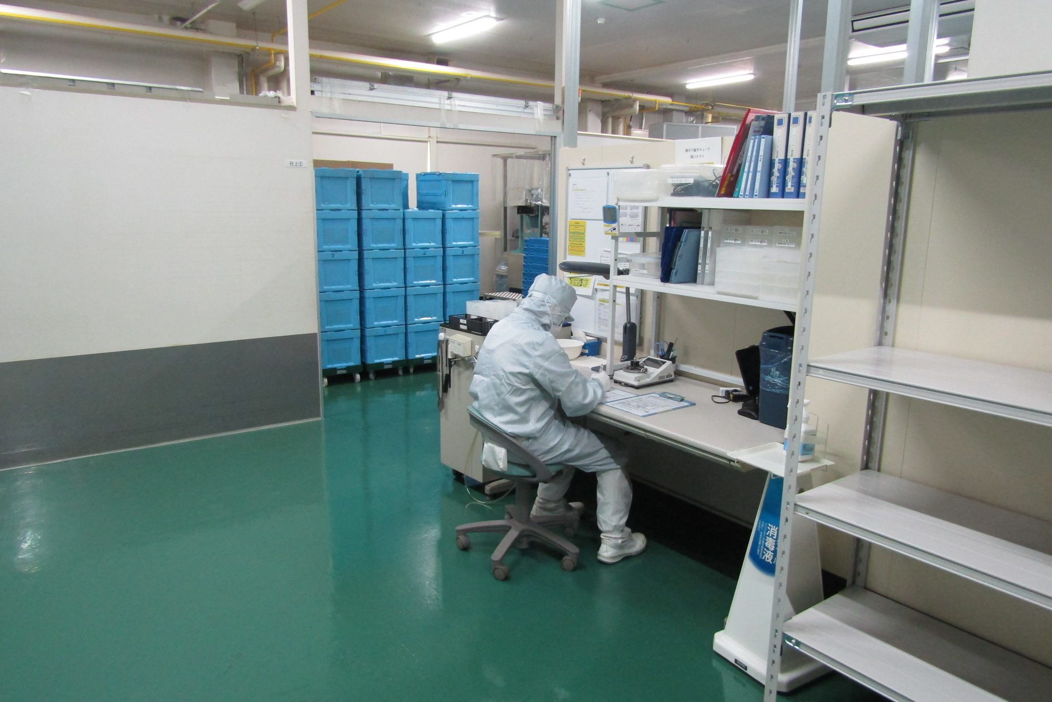 仕上げ工程の作業台。奥には製品を運ぶ青いコンテナが積まれている